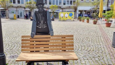 Sitzbank mit Metallfigur von Rademann auf dem Peiner Marktplatz als besondere Stadtmöblierung im urbanen Stadtraum der Innenstadt von Peine, Niedersachsen