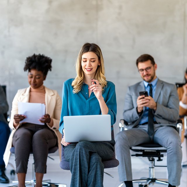 Eine Gruppe sitzender Menschen arbeitet an Laptops und Smartphones. 