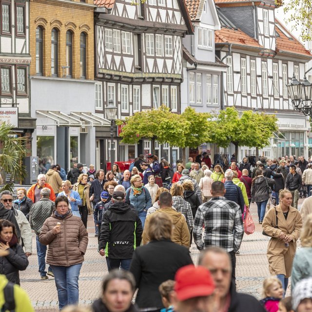 Stark frequentierte Fußgängerzone in der Peiner Innenstadt mit zahlreichen Menschen, die zwischen Geschäften, Bäumen und historischen Fassaden unterwegs sind. Die Einkaufsstraße vermittelt lebendiges Stadtleben und eine hohe Besucherfrequenz.