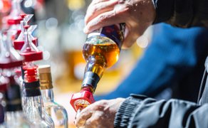 Das Bild zeigt, wie Whisky in ein Glas gegossen wird. 