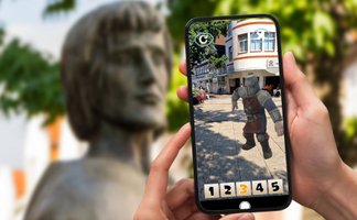 Smartphone zeigt eine Augmented-Reality-Stadtrallye in Peine: Eine virtuelle Ritterfigur erscheint auf dem Bildschirm vor einer historischen Statue in der Innenstadt.