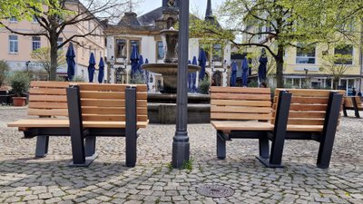 Zwei gegenüberliegende Holz-Sitzbänke auf dem Peiner Marktplatz vor dem Brunnen als Stadtmöblierung für Begegnung und Aufenthalt im urbanen Stadtraum von Peine, Niedersachsen