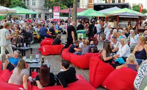 Peiner Weinfest auf dem Marktplatz mit vielen Besucherinnen und Besuchern, roten Sitzsäcken, Weinständen, grünen Sonnenschirmen und geselligem Treiben in der Innenstadt von Peine.