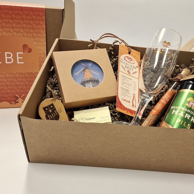 Geschenkbox „Bierliebe“ aus Peine mit einer Flasche Härke Pils, Bierglas, kleinen regionalen Produkten und dekorativer Verpackung auf einem Tisch.