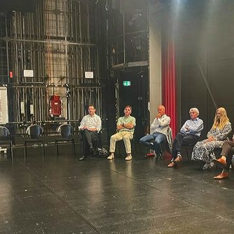 Das Bild zeigt Menschen, die auf der Bühne im Stadttheater Peiner Festsäle sitzen und an einem Workshop teilnehmen. 