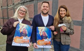 Drei Personen stehen in einer Reihe und halten Plakate hoch.