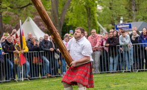 Das Bild zeigt einen Mann, der einen Baumstamm wirft, beim Highland Gathering in Peine.