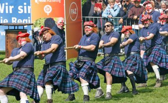 Gruppe von Männern in Kilts und karierten Mützen mit Bommel zieht gemeinsam an einem Tau im Peiner Stadtpark.