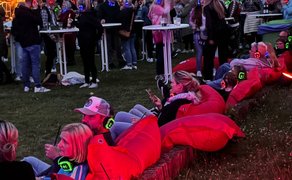 Das Bild zeigt Menschen, die auf Sitzsäcken chillen, bei der Silent Music Party im Burgpark in Peine. 