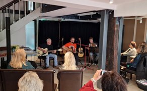 Live-Konzert im Rahmen der Kunst- und Kulturmeile im Peiner Schwan mit mehreren Musikern auf der Bühne und sitzendem Publikum in gemütlicher Innenraumatmosphäre