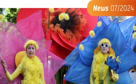 Das Bild zeigt drei Menschen, die als Blume verkleidet sind. 