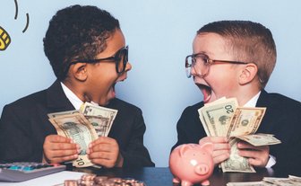 Zwei Jungen in Anzügen sitzen an einem Tisch und halten Geldscheine, auf dem Tisch liegen Münzen, ein Taschenrechner und ein Sparschwein.