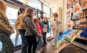 Schülerinnen lassen sich in der Tourist-Information von Peine Marketing das Sortiment des Shops zeigen.