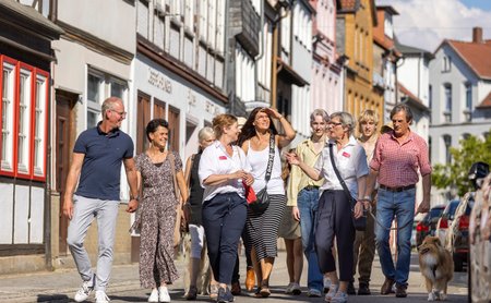Das Bild zeigt eine Gruppe Menschen, die an einer Stadtführung in Peine teilnehmen und gerade am Damm entlang laufen. 