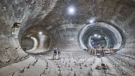 Das Bild zeigt Bergbauleute unter Tage in einer zum Teil bereits mit Beton verschalten Strecke.