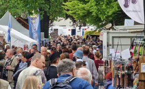Dichtes Gedränge auf dem schottischen Markt beim Highland Gathering: Zahlreiche Besucher schlendern zwischen Marktständen mit Kunsthandwerk, Schmuck und Streetfood unter grünen Bäumen – lebendige Festivalatmosphäre.
