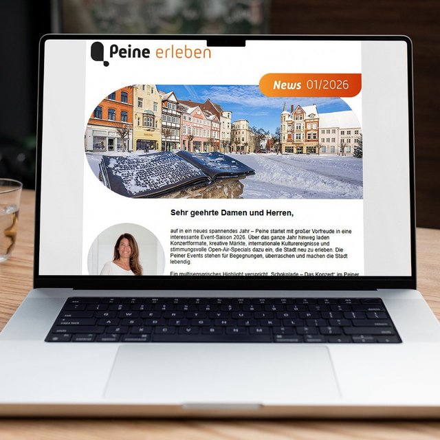 Laptop auf Holztisch zeigt Newsletter mit Überschrift „Peine erleben“ und einem Foto eines historischen Marktplatzes.