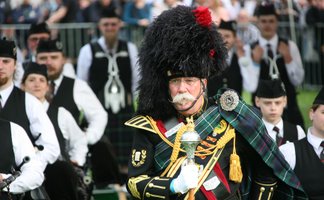 Highland Gathering in Peine mit traditionell gekleidetem Teilnehmer und Dudelsackspielern – Themen-Stadtführung zu internationalen Veranstaltungen in Peine.