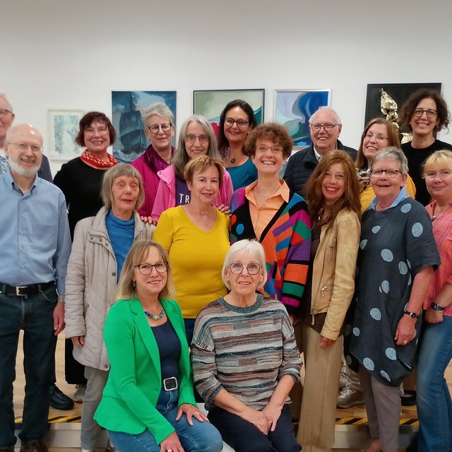 Eine Gruppe von Menschen steht in einer Kunstausstellung.  