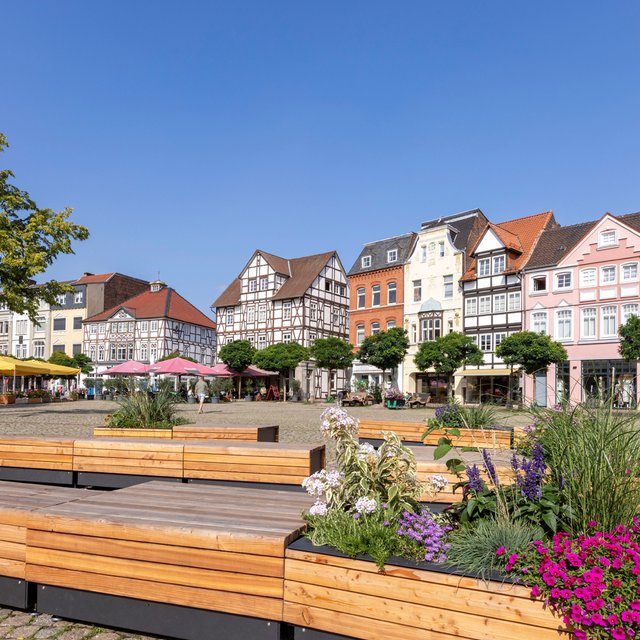 Das Bild zeigt die blühende Stadtoase, das sind Sitzgelegenheiten mit Blumenkübeln, auf dem Historischen Marktplatz in Peine. 