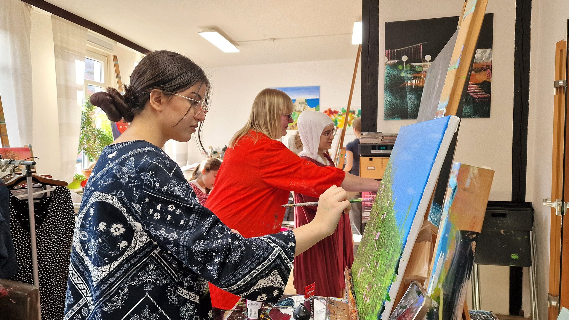 Ein Mädchen malt in einem Atelier auf einer Leinwand. 