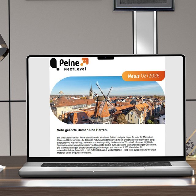 Laptop auf einem Schreibtisch zeigt den Newsletter „Peine NextLevel – News 02/2026“ mit Luftaufnahme der Peiner Innenstadt und Windmühle auf dem Bildschirm.