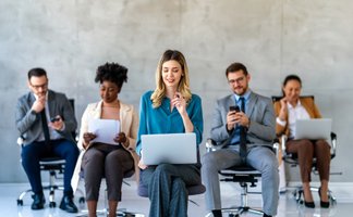 Eine Gruppe sitzender Menschen arbeitet an Laptops und Smartphones. 