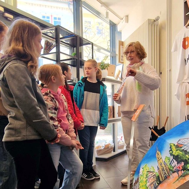 Schülerinnen lassen sich in der Tourist-Information von Peine Marketing das Sortiment des Shops zeigen.