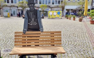 Sitzbank mit Metallfigur von Rademann auf dem Peiner Marktplatz als besondere Stadtmöblierung im urbanen Stadtraum der Innenstadt von Peine, Niedersachsen