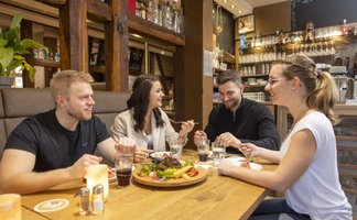 Freunde sitzen gemeinsam an einem Tisch und genießen Speisen und Getränke in einem gemütlichen Restaurant in Peine.