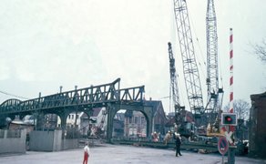 Eine teils demontierte Eisenbahnbrücke mit Stahlträgern, Kräne und Bauarbeiter bei Schweißarbeiten eines abmontierten Brückenteils.