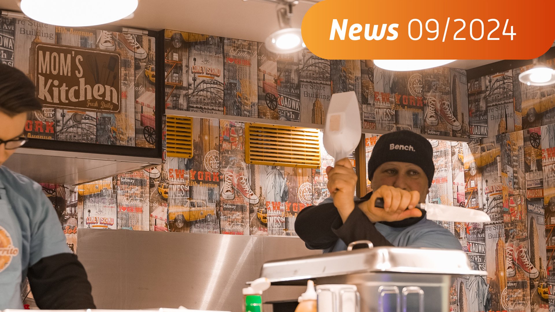 Das Foto zeigt einen Mann in einem Streetfoodwagen, der mit Küchenutensilien handtiert. 