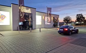 Ein Auto fährt abends an einem Gebäude mit der Aufschrift "Rausch" vorbei.