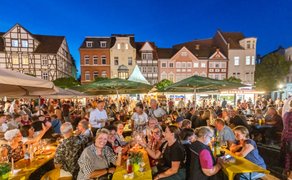 Gut besuchtes Peiner Weinfest am Abend auf dem historischen Marktplatz mit Fachwerkhäusern, langen Tafeln, Wein und geselligem Beisammensein.