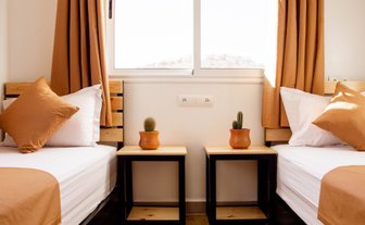 Helles Hotelzimmer mit zwei Einzelbetten, Nachttischen und gemütlicher Einrichtung für Übernachtungen in Peine.