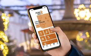 Hand hält Smartphone mit geöffneter App 'Peine2Go' und Anzeige eines lebendigen Adventskalenders mit Zahlen 1 bis 6.