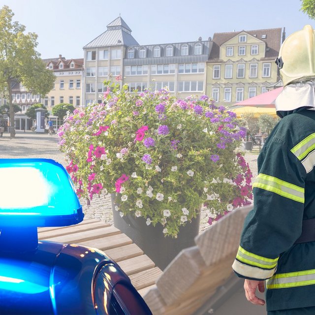 Das Bild zeigt das Blaulicht der Polizei und einen Feuerwehrmann auf dem Historischen Marktplatz in Peine. 