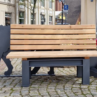Das Bild zeigt eine Bank mit einem stilisierte Wolfs dahinter auf dem Historischen Marktplatz in Peine, was als Kunst im öffentlichen Raum gilt. 