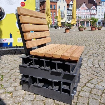 Das Bild zeigt einen Holzsessel auf dem Historischen Marktplatz in Peine, was als Kunst im öffentlichen Raum gilt. 
