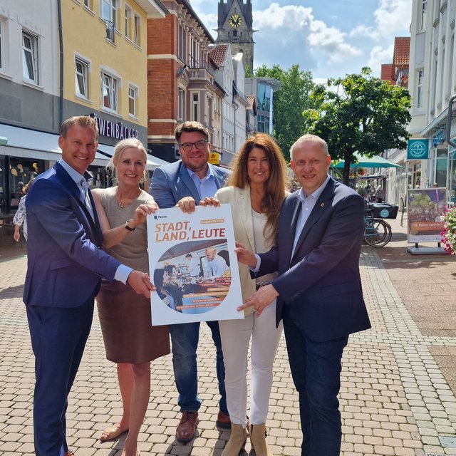 Das Bild zeigt eine Gruppe Menschen, die das neue Stadtmagazin Stadt, Land, Leute in Peine anpreisen. 
