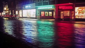 Das Bild zeigt eine alte Ansicht von Peine in der Nacht mit beleuchteten Geschäften. 