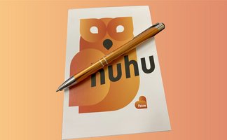 Das Bild zeigt das Peine-Schreibset, einen Blog mit Eulenmotiv und "huhu"-Schriftzug sowie einen Kugelschreiber in orange.