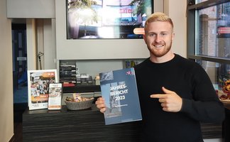 Das Bild zeigt einen jungen Mann der auf ein Magazin zeigt. 