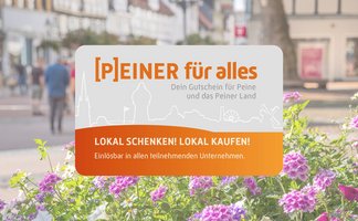 Das Bild zeigt im Fokus den Stadtgutschein Peiner für alles und dahinter die belebte Peiner Innenstadt.