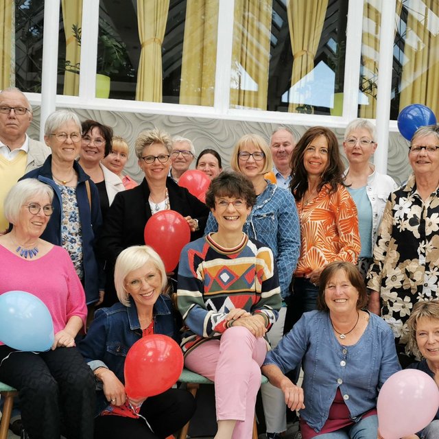 Das Bild zeigt eine Gruppe Menschen, die Luftballons in der Hand halten. 