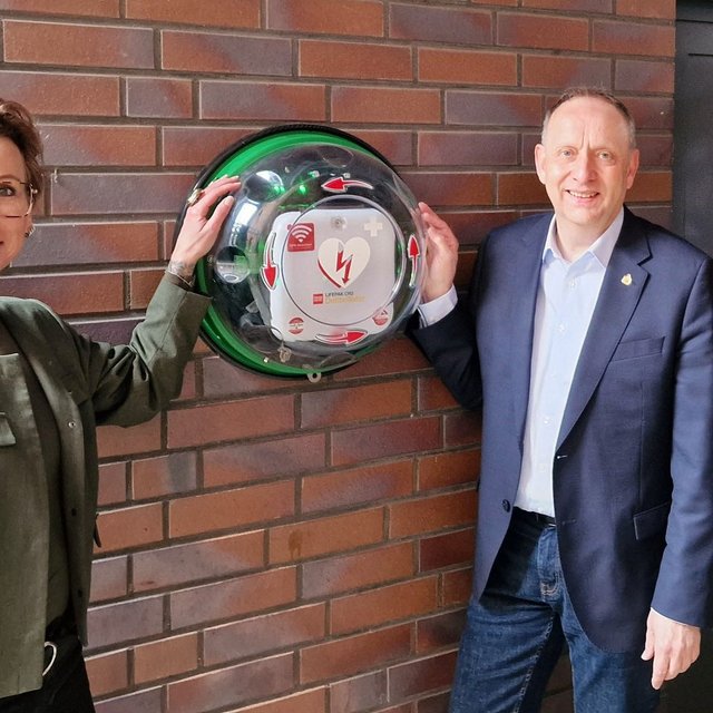 Nela Bode-Beck (Geschäftsführerin des ASB Kreisverbandes Peine), Klaus Saemann (Bürgermeister und Aufsichtsratsvorsitzender Peine Marketing) und Anja Barlen-Herbig (Geschäftsführerin Peine Marketing) zeigen den lebensrettenden Defibrillator im Hof der Geschäftsstelle von Peine Marketing. 