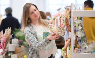 Das Bild zeigt eine Frau, die Dekoration auf einer Messe anschaut. 