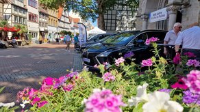 Das Bild zeigt mehrere Autos, die in der Innenstadt von Peine ausgestellt sind. Im Vordergrund befinden sich Blumenarrangement. 
