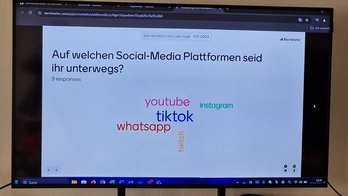 Das Bild zeigt ein TV-Gerät, auf dem Stichworte zu sehen sind. 